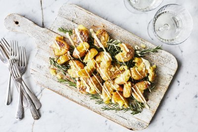 Eens een patatje in een feestjas op tafel? Serveer deze ovenaardappeltjes en ontvang veel "mmmmm-lekker complimentjes". Deze gecrushte aardappeltjes zijn geserveerd op een houten plank met een heerlijk picklessausje.  