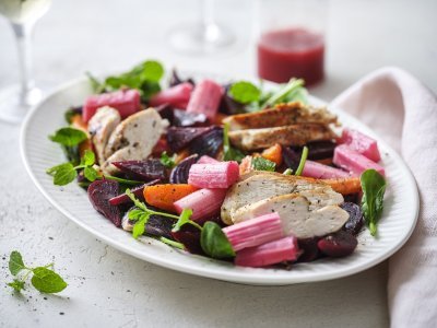 Een rijkgevuld salade die gezond is en mooi van kleur, daar word je instant vrolijk van. De salade bestaat uit frisgroene spinazie, warmoranje wortel, bloedrode bietjes, zoetroze rabarbar en goudgegrilde kip. De frambozendressing werd erbij geserveerd in een glazen kannetje. 