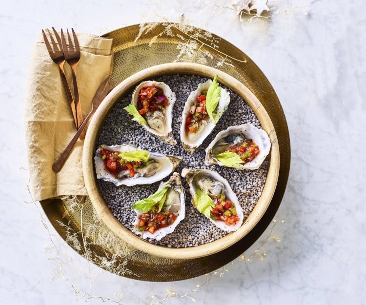 Zes oesters liggen te schitteren op de feesttafel. Ze zijn voor de helft gevuld met de vinaigrette op basis van tomatensap, stukjes paprika's en vodka. Afgewerkt met een blaadje selder die zorgt voor de frisgroene kleur bij de rode topping.