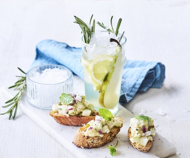 Rozemarijnlimonade met peer staat op tafel, klaar om te proeven. Wij serveren hem met burschetta met perensalsa en blauwe schimmelkaas