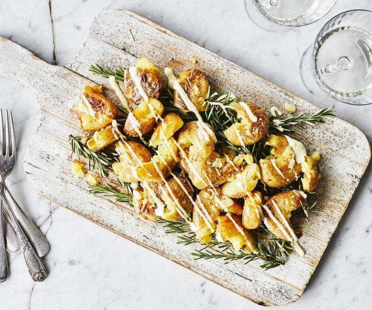 Eens een patatje in een feestjas op tafel? Serveer deze ovenaardappeltjes en ontvang veel "mmmmm-lekker complimentjes". Deze gecrushte aardappeltjes zijn geserveerd op een houten plank met een heerlijk picklessausje.  