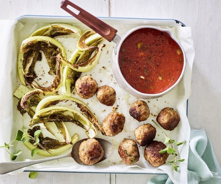 Gegrilde bloemkoolbladeren liggen op de ovenschaal met gehaktballetjes en tomatensaus in een sauspannetje. 