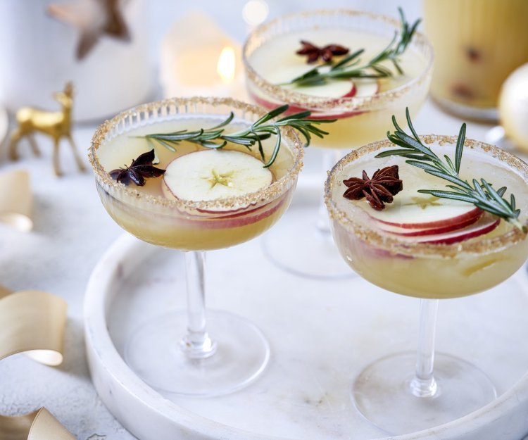 Een heerlijk aperitief voor de eindejaarsperiode. Op een serveerschoteltje staan 3 mooie glazen gevuld met onze punch van appel en gemberbier. Hij is afgewerkt met een schijfje appel en een takje rozemarijn, dat het net die feestelijke toets geeft. Santé op het nieuwe jaar.