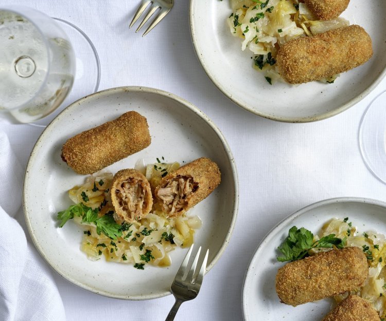 Meerdere kroketten liggen op kleine bleke bordjes. Ze worden geserveerd met huisgemaakte chutney van witloof. 