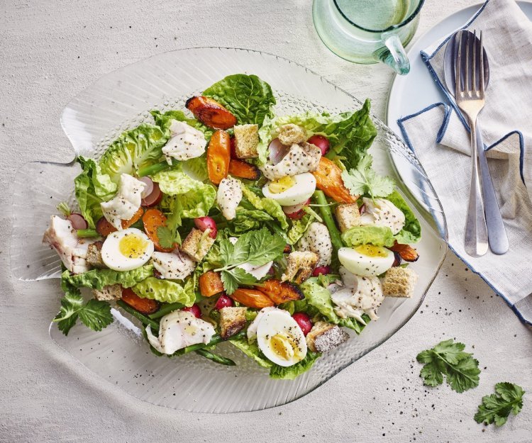 Een goed gevulde schaal met een groene salade, enkele oranje wortels en gekookte eitjes. Stukjes rode poon werden toegevoegd voor extra smaak, natuurlijk.