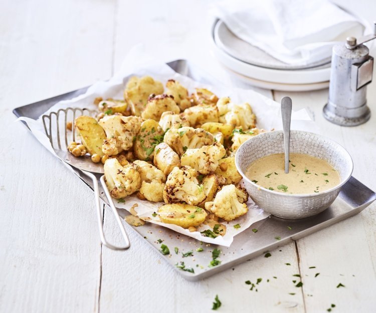 Een ovenschotel gevul de goud! Zo ziet hij er eigenlijk een beetje uit. De ovenschotel is bestaat nl uit kleine aardappelen, kikkererwten en bloemkoolroosjes. We dienen hem op met een heerlijk sausje op basis van tahini. Alles afgewerkt met groene snippers van de peterselie. 