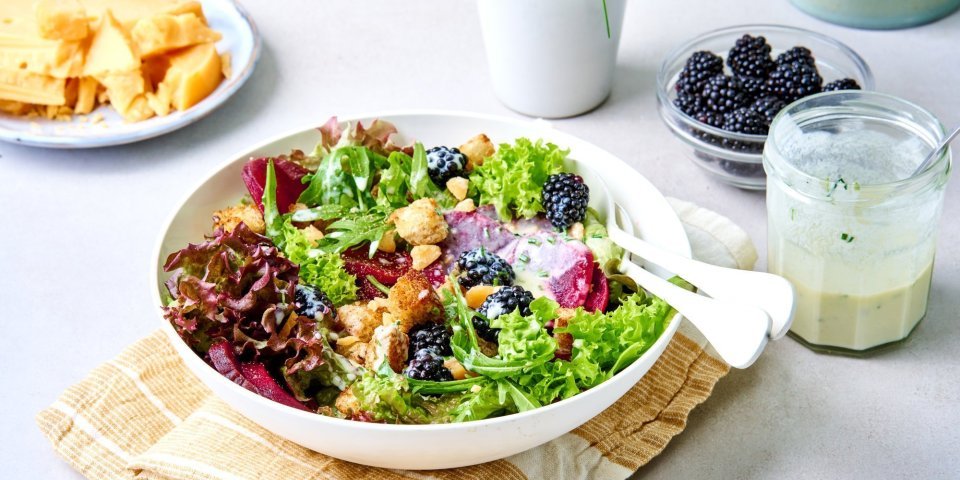 Een heerlijke rijkgevulde salade staat te wachten op jou. Het bord is gevuld met sla, braambessen, rode biet en Flandrienkaas. De dressing op basis van karnemelk staat er langs. 