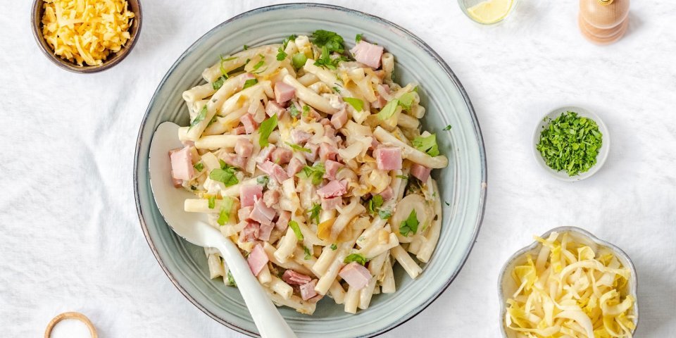 Macaroni met ham, roomkaas en witloof geserveerd in een diep bord. 