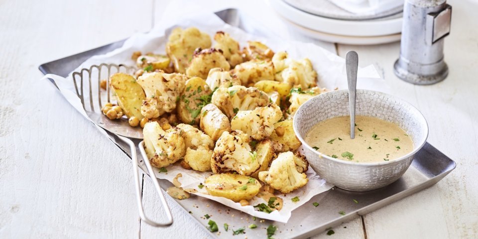 Een ovenschotel gevul de goud! Zo ziet hij er eigenlijk een beetje uit. De ovenschotel is bestaat nl uit kleine aardappelen, kikkererwten en bloemkoolroosjes. We dienen hem op met een heerlijk sausje op basis van tahini. Alles afgewerkt met groene snippers van de peterselie. 