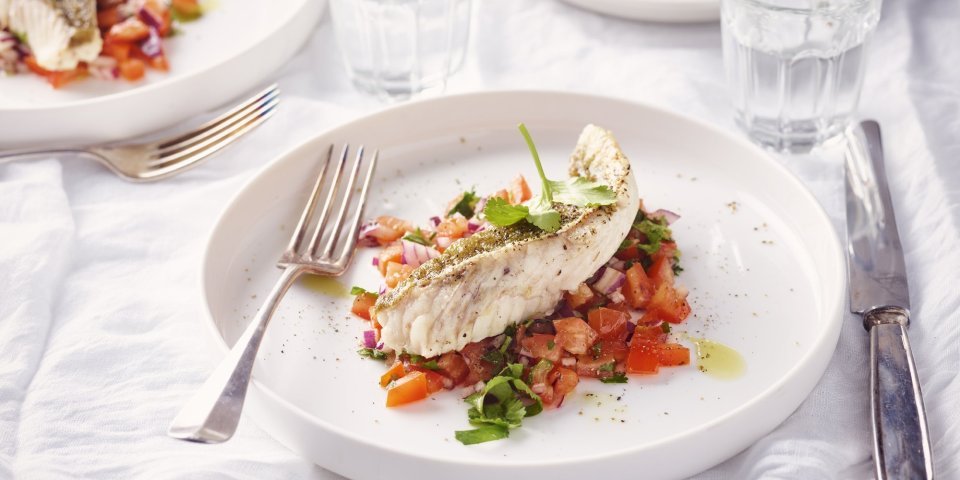 Een rond bordje staat op tafel. De kleurrijke tomatensalsa springt in het oog, hierop ligt een stukje vis. Rode poon, lekker van bij ons.  