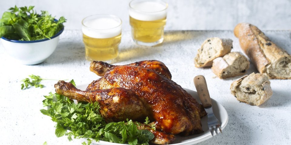 Een volledige kip op de BBQ op een blikje bier klaargemaakt, dit noemen we canned chicken. Deze kip kreeg een kruidige jas aan door de BBQ-saus. Ze ligt op een kruidige salade klaar om te knippen in stukken en op te peuzelen. 