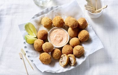 Bitterballen liggen te schitteren op een groot bord. In het midden staat een schaaltje met de pikante dipsaus en enkele partjes limoen. 