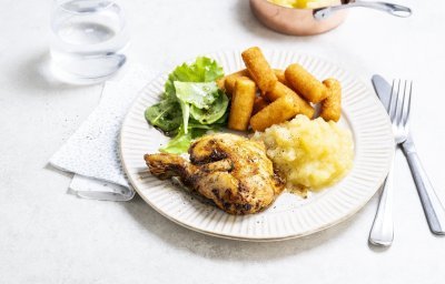 Op tafel staat een bord klaar met een gebraden kippenbout, goudgele appelmoes en kroketten. We serveren deze klassieker met nog wat extra sla en ev nog wat appelmoees. 