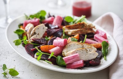 Een rijkgevuld salade die gezond is en mooi van kleur, daar word je instant vrolijk van. De salade bestaat uit frisgroene spinazie, warmoranje wortel, bloedrode bietjes, zoetroze rabarbar en goudgegrilde kip. De frambozendressing werd erbij geserveerd in een glazen kannetje. 