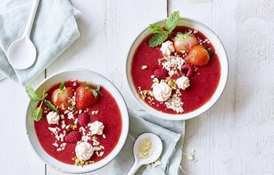 Twee kleine kommetjes zijn gevuld met de rode dessertsoep op basis van aardbei en framboos. Het zijn net kunstwerkjes, door de afwerking met meringue, verse muntblaadjes, nootjes en witte chocoladeschilfers.