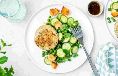 Een burger van vis? Yep, dit is er eentje van heek met een groene salade van erwtjes en komkommer. Langs het bord staat een klein sauspotje met de vinaigrette om zelf toe te voegen.